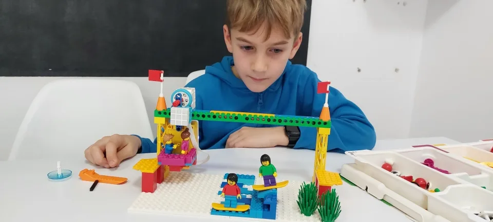 Dziecko skupione na budowaniu robota LEGO podczas warsztatów FA-BRYKA